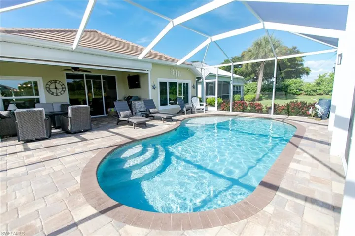 View of pool with a lanai, a patio area, and ceiling fan