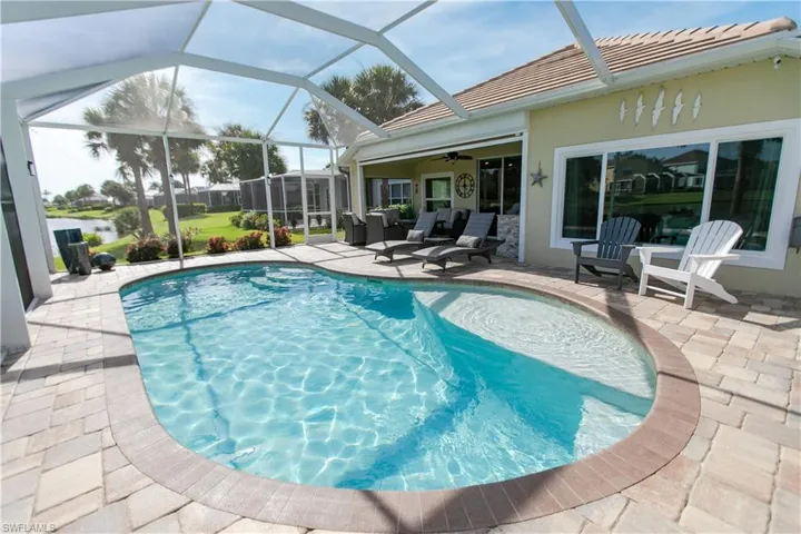 View of pool with ceiling fan, glass enclosure, a patio area, and an outdoor hangout area