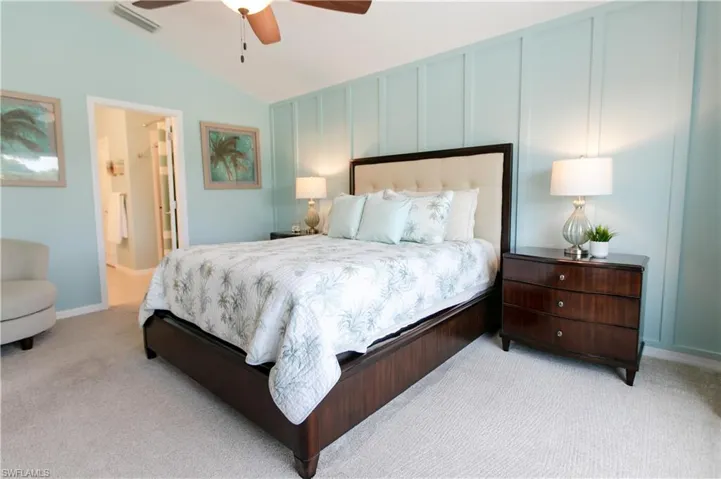 Bedroom with vaulted ceiling, light carpet, ensuite bathroom, and ceiling fan