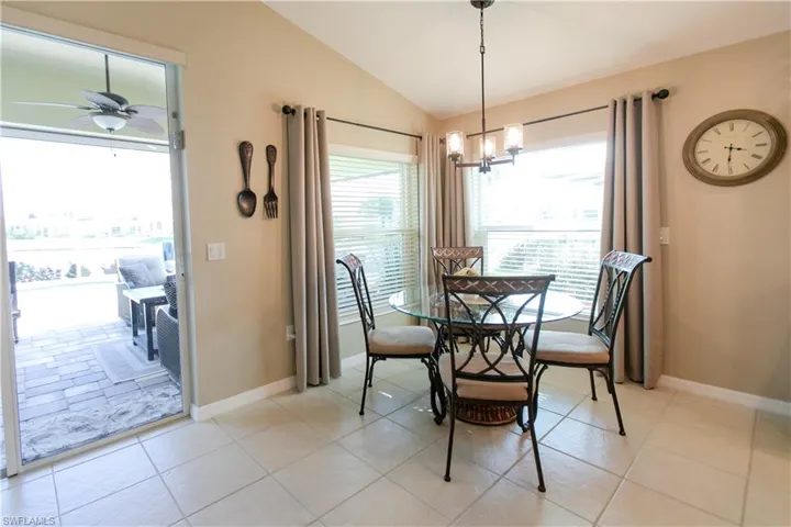Dining area featuring ceiling fan with notable chandelier, lofted ceiling, and light tile floors