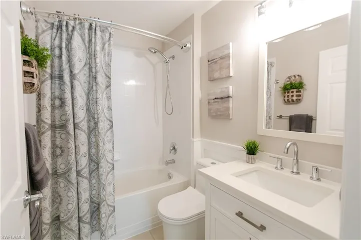 Full bathroom with tile floors, shower / bathtub combination with curtain, toilet, and vanity