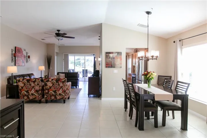 Dining space featuring lofted ceiling, light tile floors, and ceiling fan with notable chandelier
