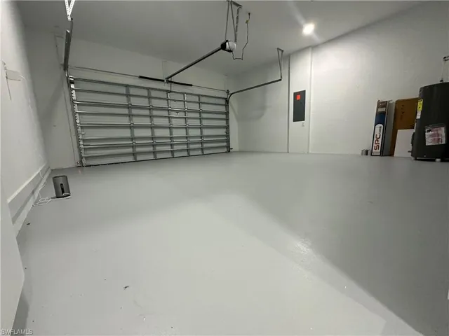 Garage featuring a garage door opener, electric panel, and water heater