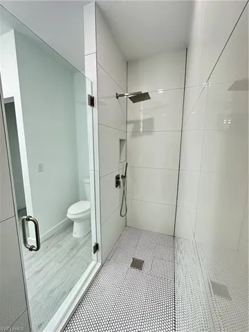 Bathroom featuring a shower with shower door and toilet