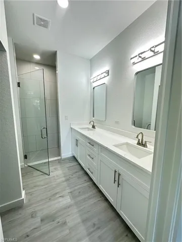 Bathroom featuring hardwood / wood-style floors, vanity, a shower with shower door, and a textured ceiling
