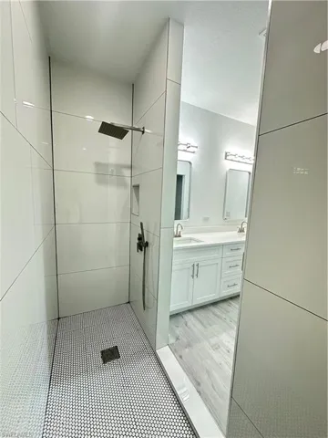 Bathroom featuring hardwood / wood-style floors, vanity, and a tile shower