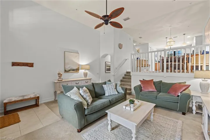 Living room with high vaulted ceiling, ceiling fan, and light tile patterned floors