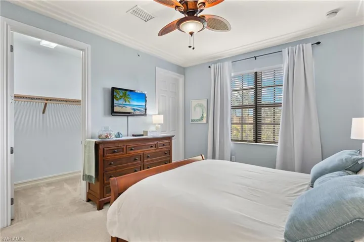 Carpeted bedroom featuring ornamental molding and ceiling fan