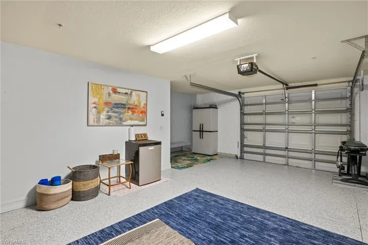 Garage featuring white fridge, a garage door opener, and refrigerator