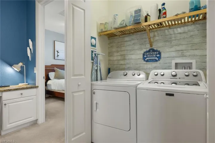 Laundry area with separate washer and dryer, wood walls, and light colored carpet