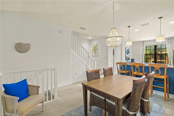 Carpeted dining room with a notable chandelier