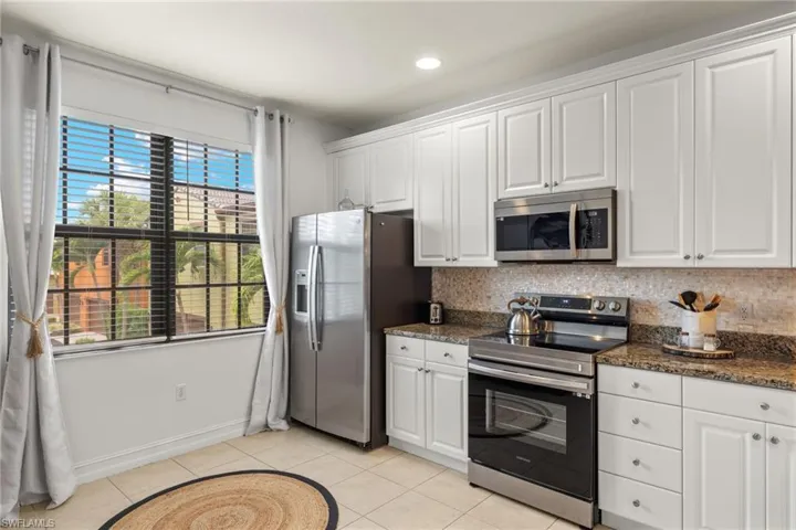 Kitchen featuring white cabinetry, decorative backsplash, stainless steel appliances, and light tile patterned floors