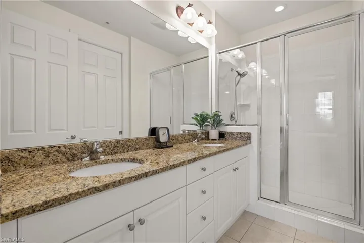 Bathroom with a shower with door, double vanity, and tile patterned floors