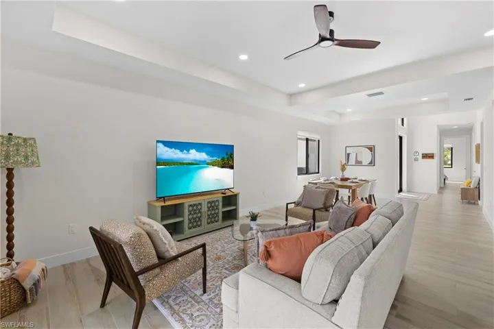 Open-concept living area featuring a tray ceiling, recessed lighting, and wood-finish flooring