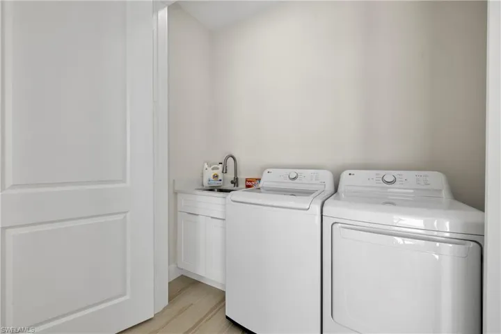 Dedicated laundry area featuring a utility sink with a gooseneck faucet, white cabinetry, and a light-toned countertop