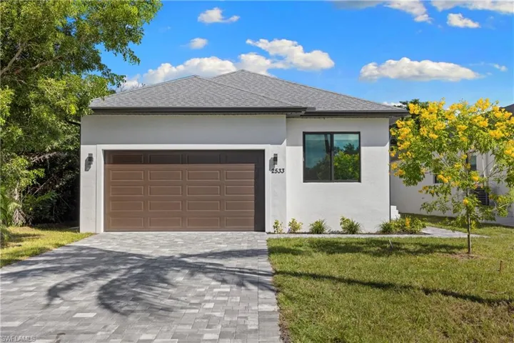 Modern single-story residence featuring a gray shingle roof, white stucco exterior, and a brown paneled garage door