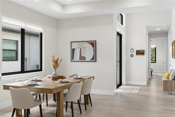 Open-concept dining area featuring light wood-finish flooring and a tray ceiling