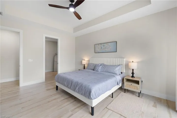 Spacious room with wood-finish tile flooring, tray ceiling, and a modern ceiling fan