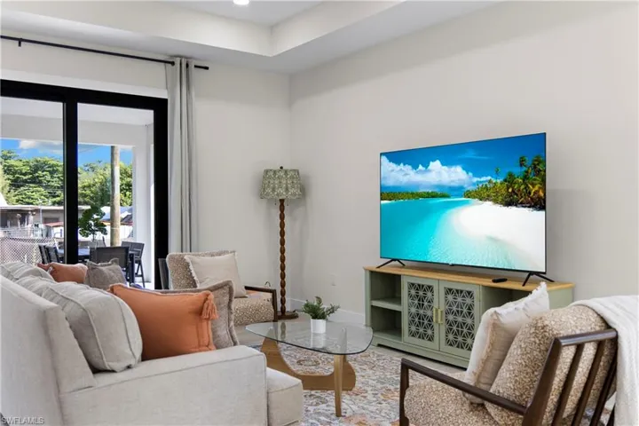 Spacious living area featuring large sliding glass doors, a tray ceiling, and light-toned walls
