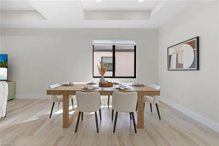 Spacious dining area featuring wood-finish flooring, recessed lighting, and tray ceilings
