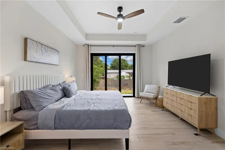 Recessed ceiling with a modern ceiling fan, light wood-finish flooring, and a full-light glass door leading to the exterior