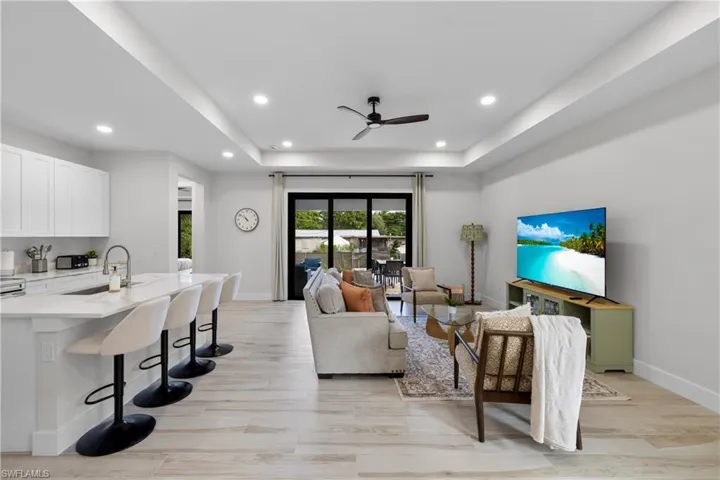 Open-concept living area featuring light wood-finish flooring, recessed lighting, and a modern ceiling fan