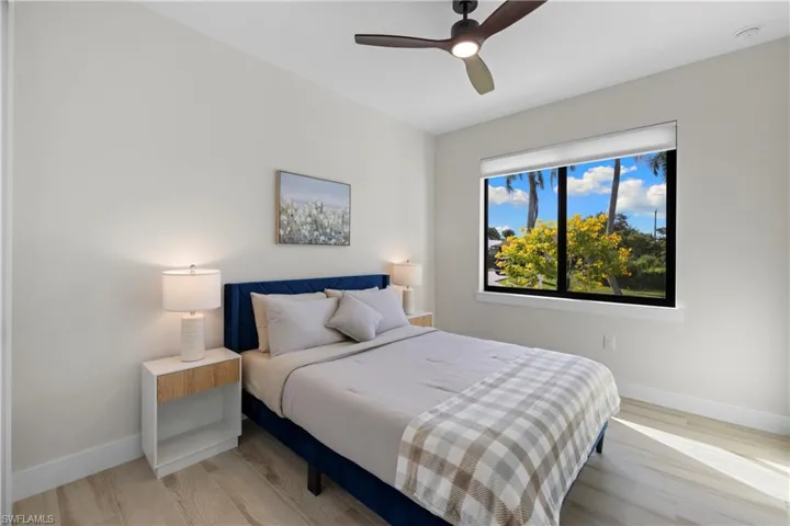 Bright room featuring a large window, wood-finish flooring, a contemporary ceiling fan, and crisp white walls