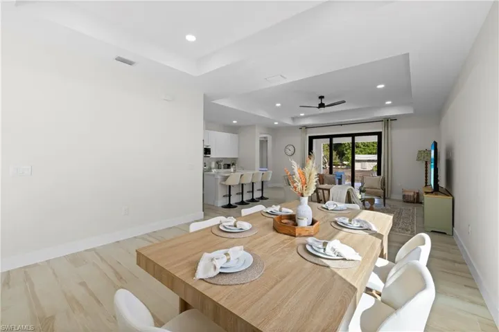 Open-concept dining area featuring wood-finish flooring, recessed lighting, and a tray ceiling