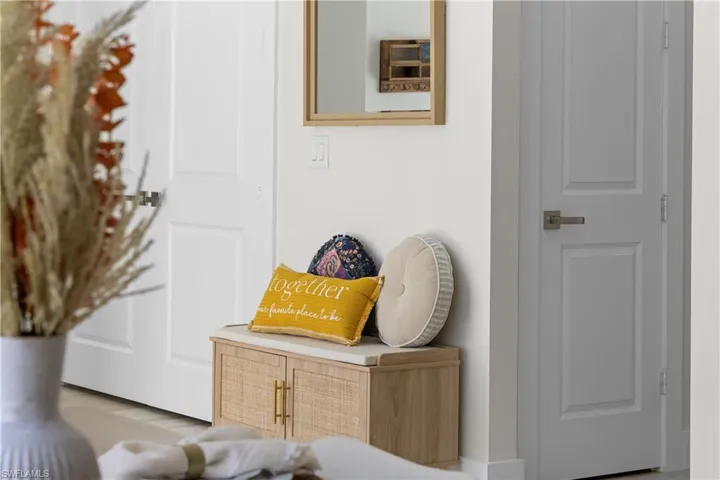 Entryway featuring a built-in wood-finish cabinet with woven panels and gold-tone hardware, topped with a light-toned surface