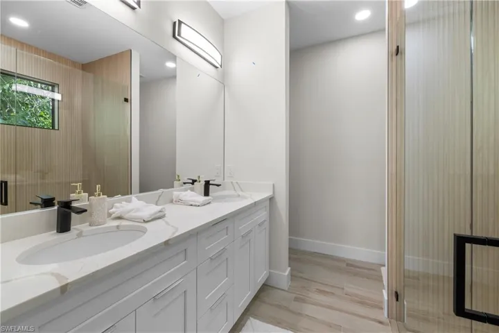 Contemporary bathroom featuring a double vanity with stone countertops, integrated sinks, and matte black faucets