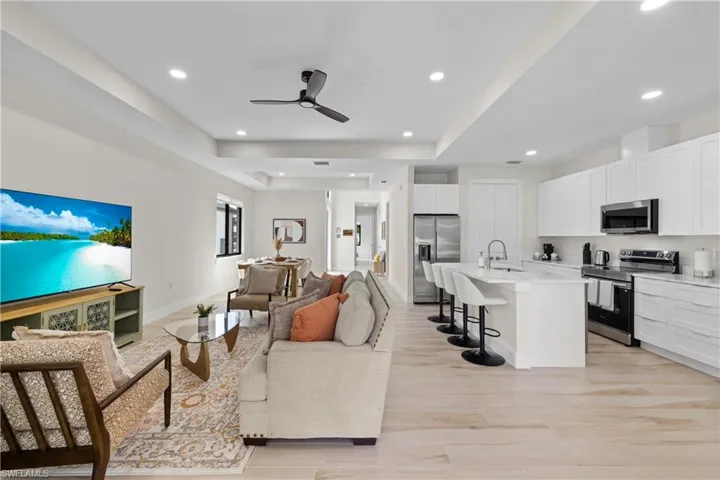 Open concept living space featuring wood-finish flooring and a tray ceiling with recessed lighting