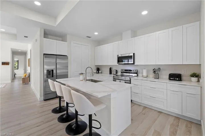 Bright kitchen featuring white shaker cabinetry and a large central island with seating