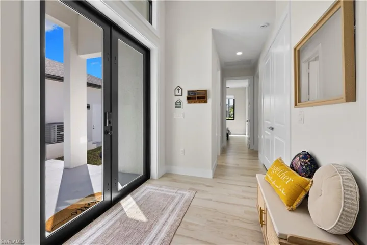 Entryway featuring expansive glass-paneled double doors, light wood-finish flooring, recessed lighting, and white baseboards
