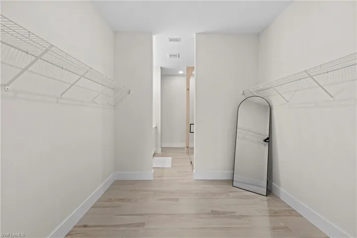 Spacious walk-in closet featuring light wood-finish flooring and extensive wire shelving