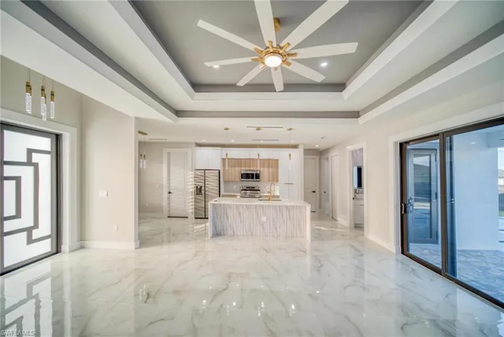 Unfurnished living room featuring sink, ceiling fan, and a tray ceiling