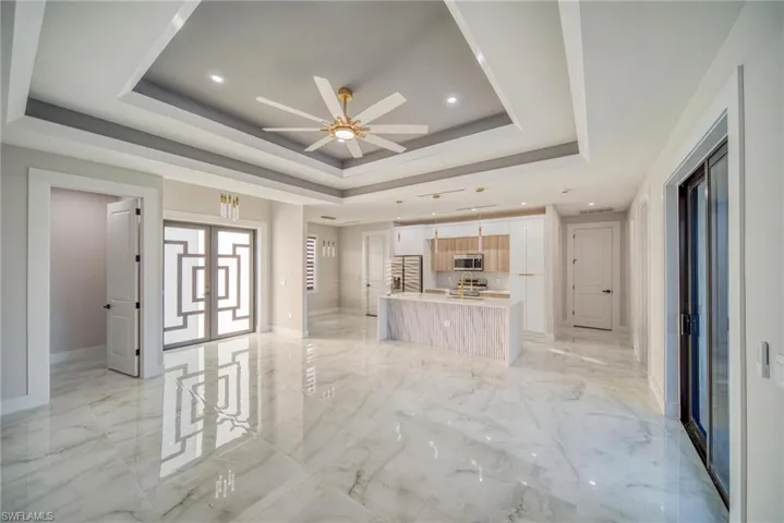 Unfurnished living room featuring a tray ceiling and ceiling fan