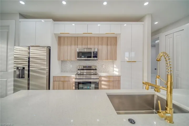 Kitchen featuring white cabinets, stainless steel appliances, sink, and backsplash