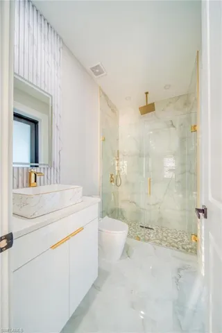 Bathroom featuring a shower with door, vanity, and toilet