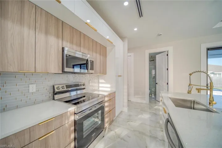 Kitchen featuring sink, light brown cabinets, stainless steel appliances, and backsplash