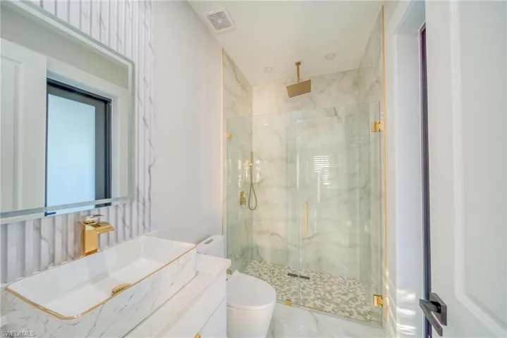 Bathroom with vanity, a shower with shower door, and toilet