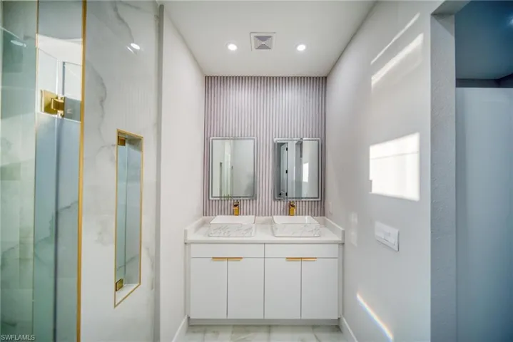 Bathroom featuring a shower with door and vanity