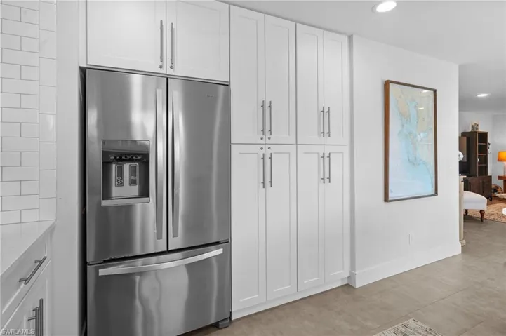 Kitchen with stainless steel fridge with ice dispenser, white cabinetry, recessed lighting, and light stone countertops