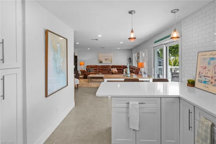 Kitchen with pendant lighting, open floor plan, light stone countertops, a peninsula, and recessed lighting