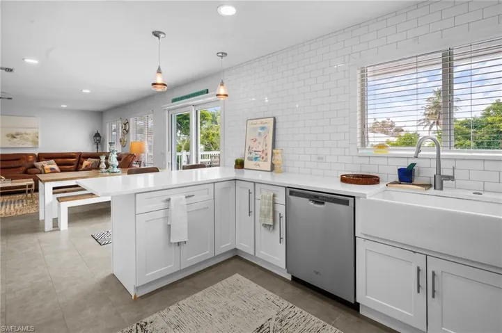 Kitchen featuring a peninsula, stainless steel dishwasher, hanging light fixtures, light stone countertops, and recessed lighting