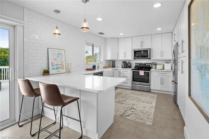 Kitchen featuring a peninsula, stainless steel appliances, a breakfast bar, tasteful backsplash, and recessed lighting