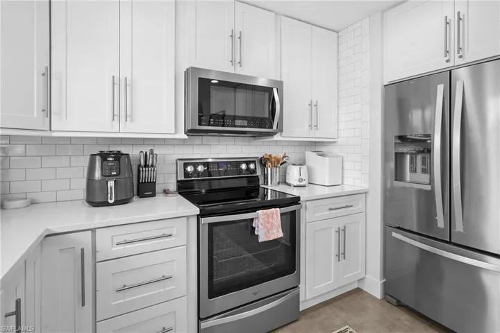 Kitchen featuring appliances with stainless steel finishes, white cabinets, and backsplash