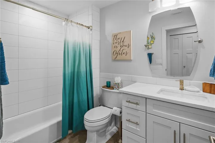 Full bathroom featuring vanity, shower / bath combo with shower curtain, and tile walls