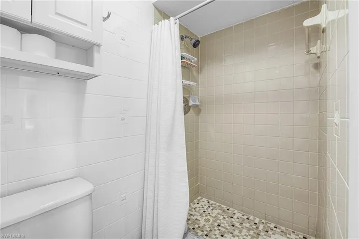 Bathroom featuring a shower stall and tile walls