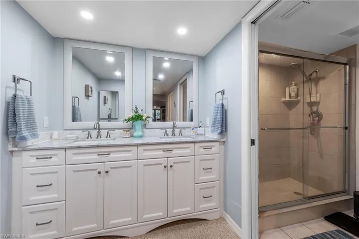 Bathroom featuring double vanity, a shower stall, and recessed lighting