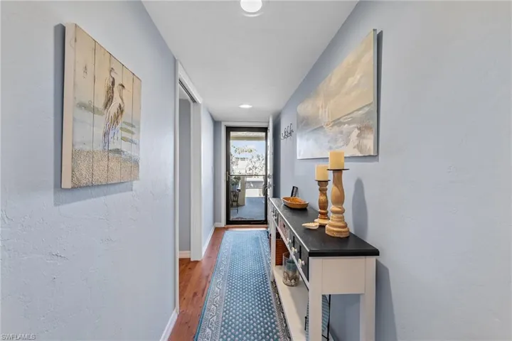 Hallway with wood finished floors, a textured wall, and recessed lighting